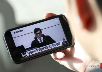 [포토] 휴대전화로 윤석열 전 대통령 1심 선고 보는 시민
